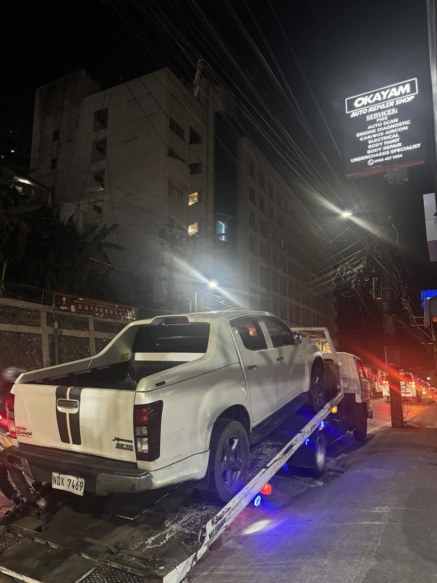 A white Isuzu D-Max pickup on the Okayam flatbed at night on Magsaysay Avenue